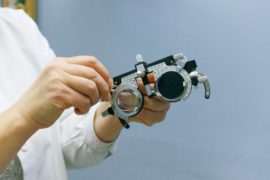 Close-up of hands adjusting an optical trial frame against a blue background, emphasizing precision and professionalism.