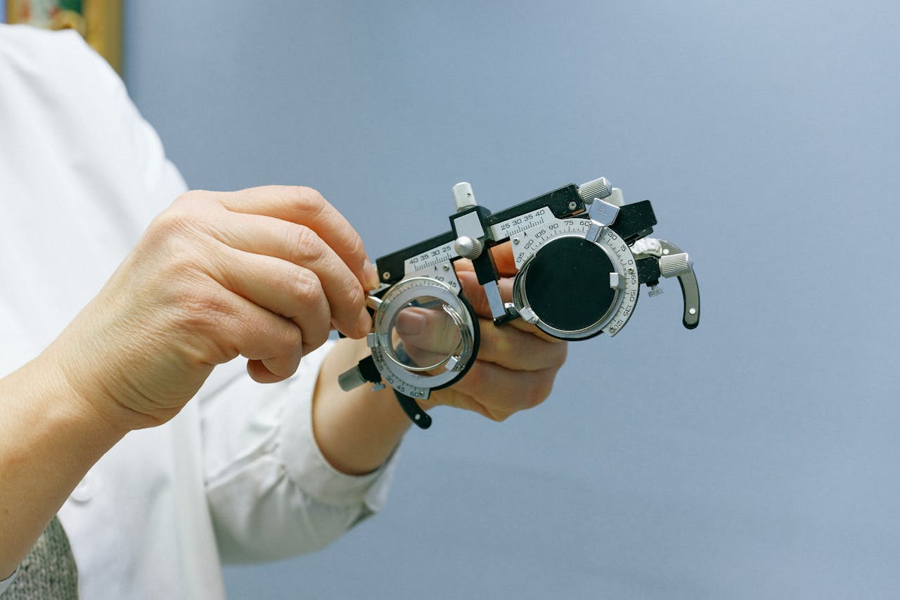 Close-up of hands adjusting an optical trial frame against a blue background, emphasizing precision and professionalism.